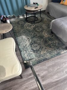 A specialist performing water extraction on a carpet and a wet chair in a living room for The Recover Tech Restoration in Vancouver, WA.
