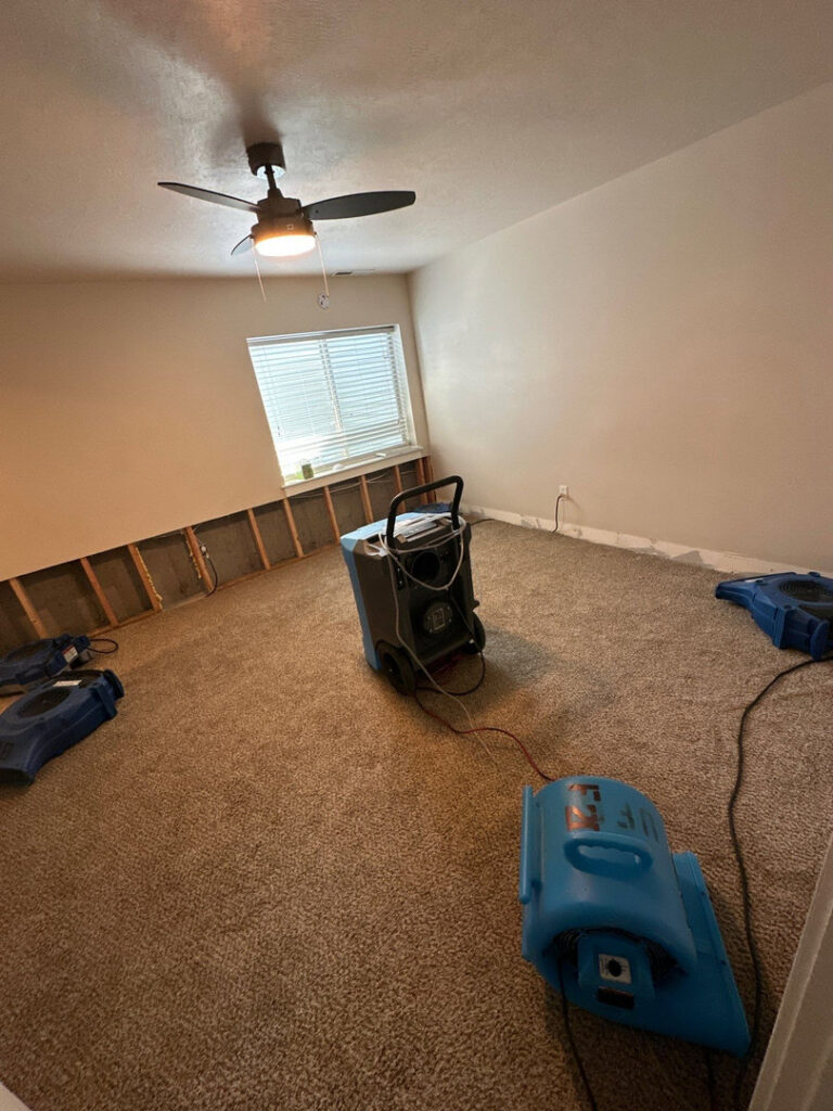 A carpeted room with walls removed and drying equipment for water damage restoration by Utah Flood Guys in Sandy, UT.