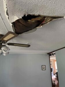 A ceiling with a large hole from water damage, exposing joists, requiring repair by RestoPros of Hartford in West Hartford, CT.