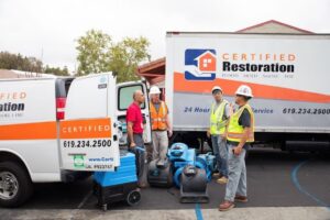 Certified Restoration crew with water damage restoration equipment and vehicles on a job site in San Diego, CA