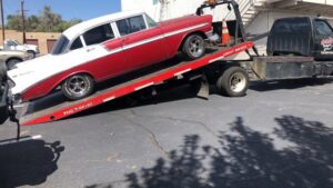 A classic red and white car being loaded onto a flatbed tow truck by A-ROD Towing in Denver, CO.