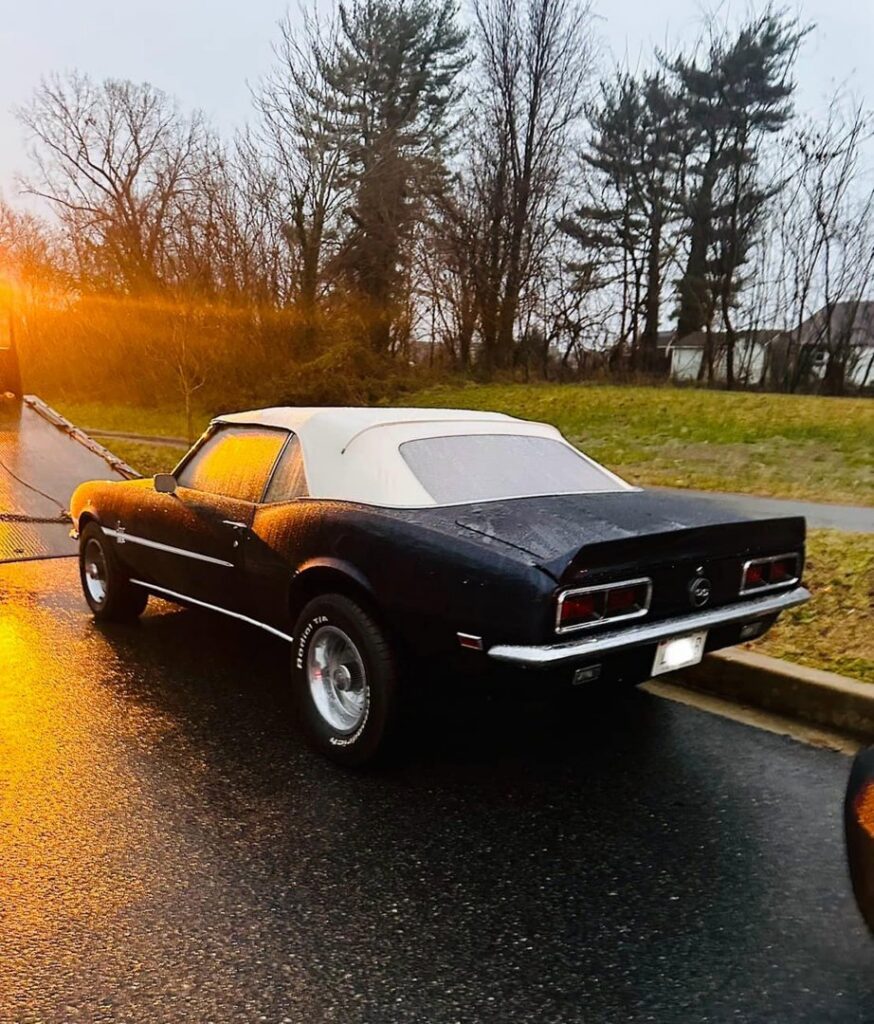 A flatbed tow truck transporting a black classic convertible car for Southern Maryland Towing in Prince Frederick, MD.