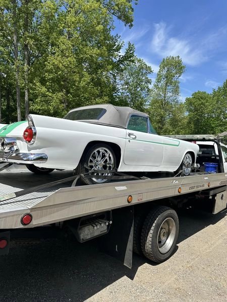 A flatbed tow truck transporting a white classic convertible car for Southern Maryland Towing in Prince Frederick, MD.