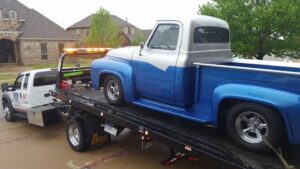 A classic blue and silver pickup truck being transported on a flatbed tow truck by 918 Wrecker Service in Tulsa, OK.