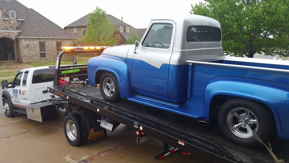 A classic blue and silver pickup truck being transported on a flatbed tow truck by 918 Wrecker Service in Tulsa, OK.