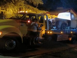 An older model truck being transported on a yellow flatbed tow truck by A&A Towing Services in Bakersfield, CA.