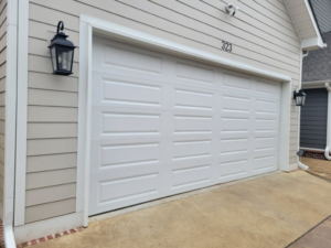 A classic white paneled garage door on a light beige house, installed by Garage Door Sales & Repair in Conway, AR.