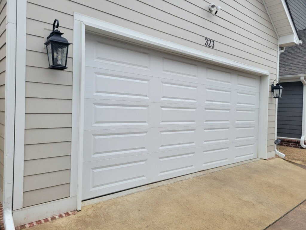 A classic white paneled garage door on a light beige house, installed by Garage Door Sales & Repair in Conway, AR.