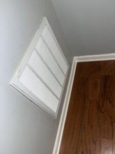 A clean air vent on a wall above a wooden floor, showcasing the detailed cleaning services provided by Royal Madam Cleaning LLC in Charlotte, NC.