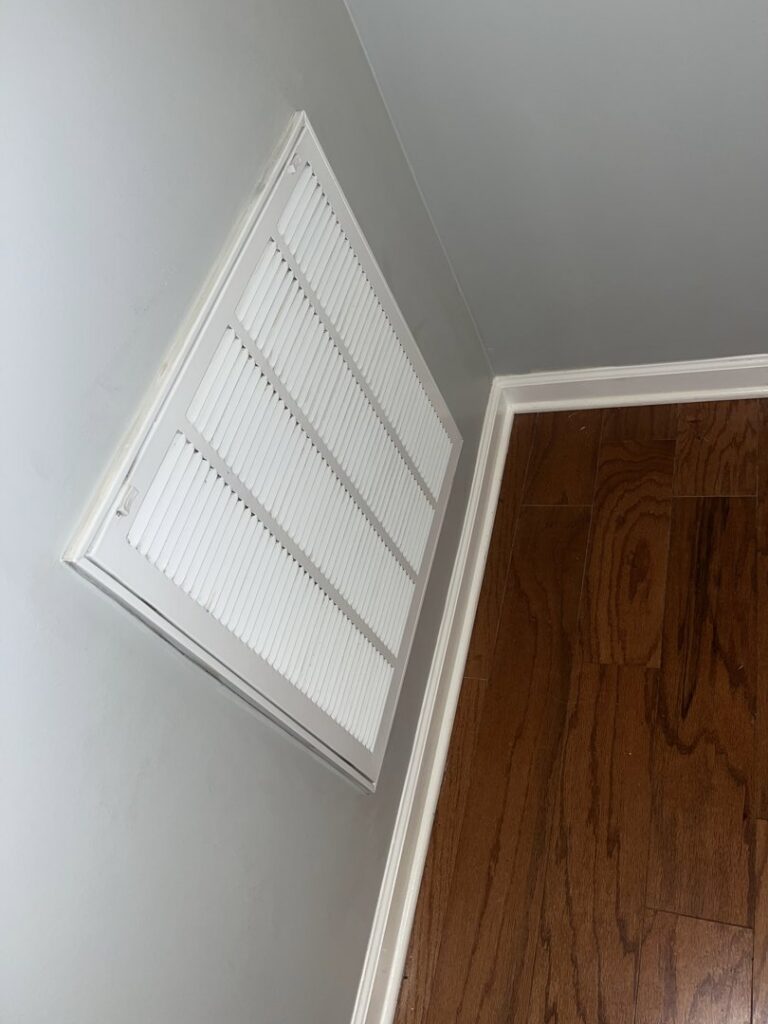 A clean air vent on a wall above a wooden floor, showcasing the detailed cleaning services provided by Royal Madam Cleaning LLC in Charlotte, NC.