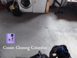 A sparkling clean basement floor with a few remaining trash bags, demonstrating a completed service by Cousin Cleaning Columbus, OH.