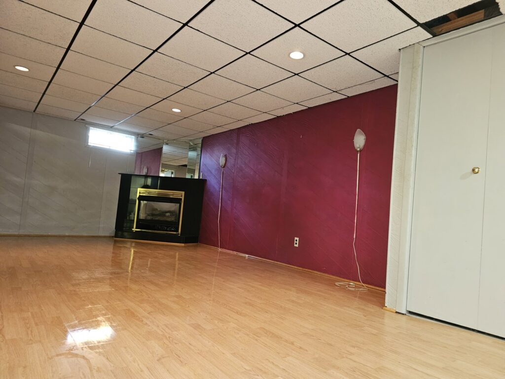 A freshly cleaned basement room with a modern fireplace and shiny wood floors, showcasing house cleaning by Way Too Bright Services LLC in Rockford, IL.