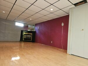 A freshly cleaned basement room with a modern fireplace and shiny wood floors, showcasing house cleaning by Way Too Bright Services LLC in Rockford, IL.