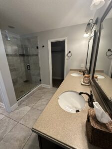 A clean bathroom featuring a double vanity and a modern glass shower, showcasing the quality cleaning by CLEAN That SHEET LLC in Jacksonville, FL.
