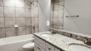 A clean bathroom with a double vanity, granite countertops, and tiled shower, expertly cleaned by Tessa's Cleaning Service in Chesapeake, VA.