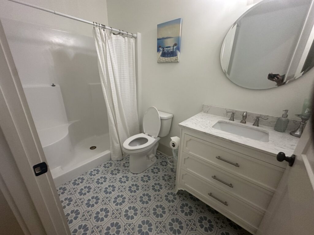 A spotless bathroom with a walk-in shower and white vanity, featuring patterned floor tiles, cleaned by Top-Notch Tidy Services in Chesapeake, VA.