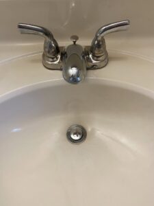 A clean white bathroom sink with a shiny chrome faucet after professional cleaning by Jenny Can Cleaning Company in Canton, OH