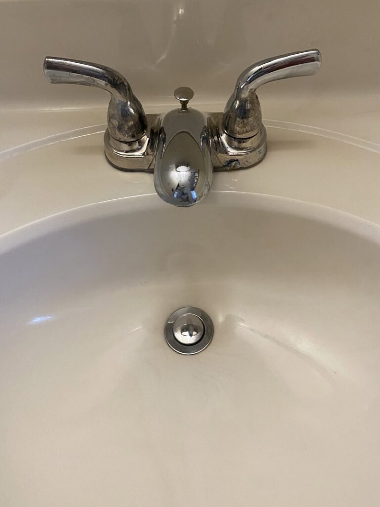 A clean white bathroom sink with a shiny chrome faucet after professional cleaning by Jenny Can Cleaning Company in Canton, OH