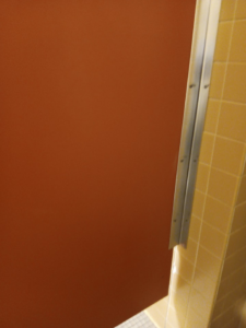 A clean bathroom stall partition and tiled wall, showcasing the detailed cleaning by Janice Janitorial LLC in Baton Rouge, LA.