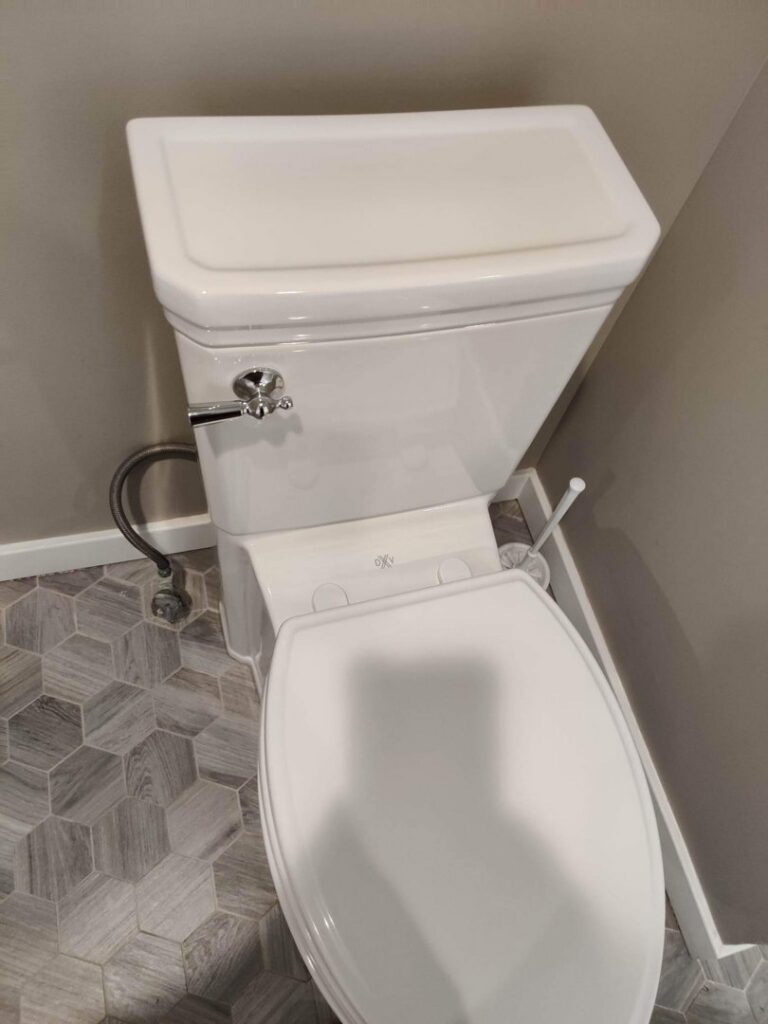 A clean toilet in a bathroom with modern hexagonal tiles after professional cleaning by Rebeccas Customized Cleaning LLC in Reading, PA.