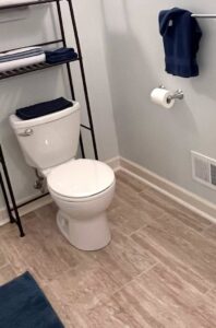 A clean bathroom with a sparkling toilet and neatly arranged shelving, showcasing the results of Nichelle's touch housekeeping LLC in Detroit, MI.