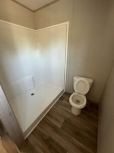 A clean bathroom with a toilet and a white shower stall, demonstrating the thorough cleaning services from CLEAN That SHEET LLC in Jacksonville, FL.