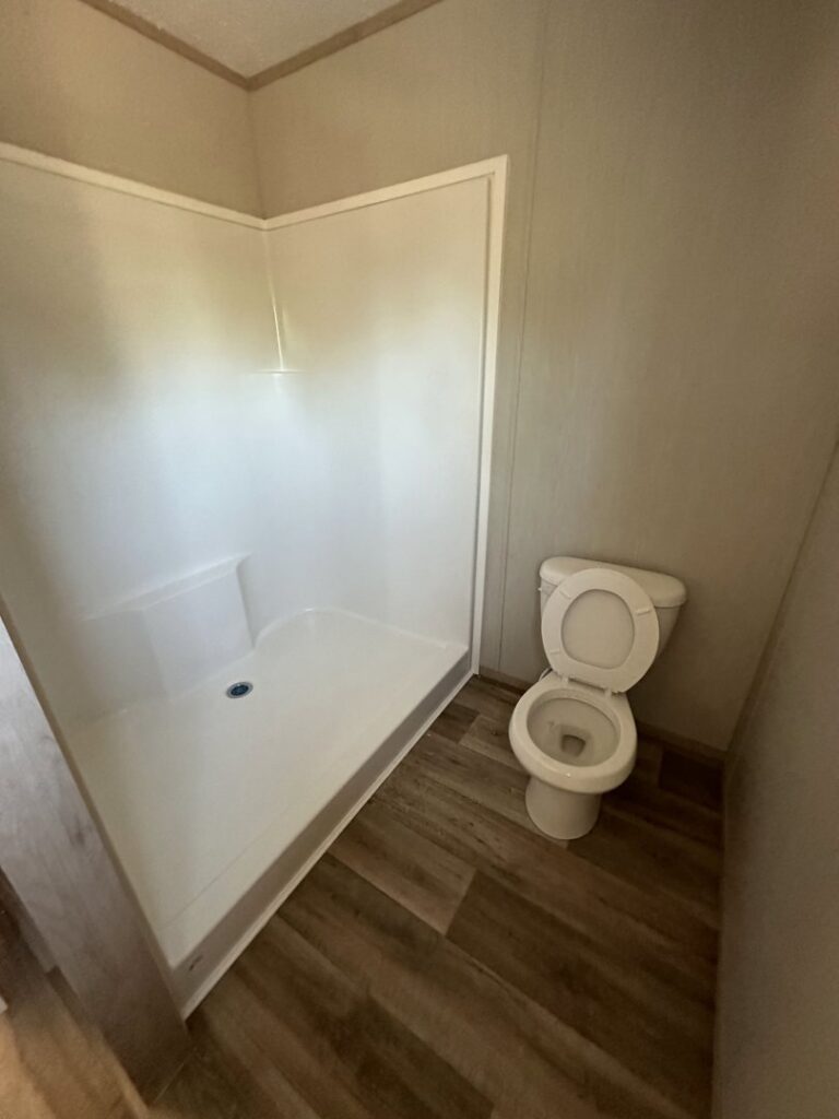 A clean bathroom with a toilet and a white shower stall, demonstrating the thorough cleaning services from CLEAN That SHEET LLC in Jacksonville, FL.