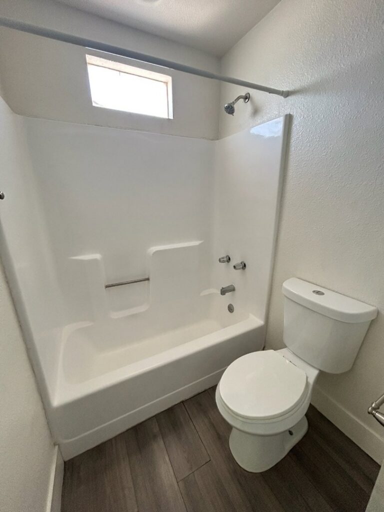 A pristine bathroom featuring a clean toilet and a sparkling shower-tub combination, expertly cleaned by Carole's House Cleaning in Tempe, AZ.