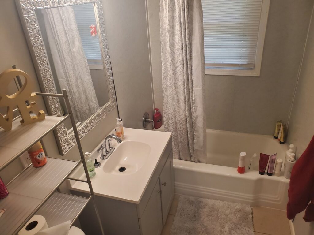 A clean bathroom vanity with a sink and mirror, showcasing the meticulous cleaning services of Perfection Cleaning in Kansas City, MO.