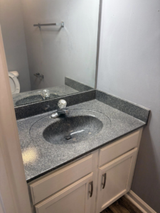A clean bathroom vanity with a speckled countertop, sink, and mirror, showcasing the detailed bathroom cleaning by Claudia's Cleaning Services in Clarksville, TN.