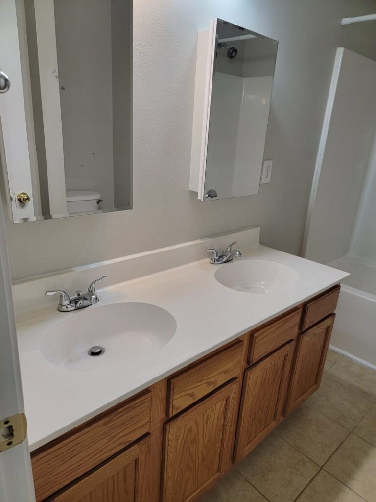 A clean bathroom vanity with double sinks and wooden cabinets, showcasing the detailed cleaning by AG Simply Clean in Concord, NC.