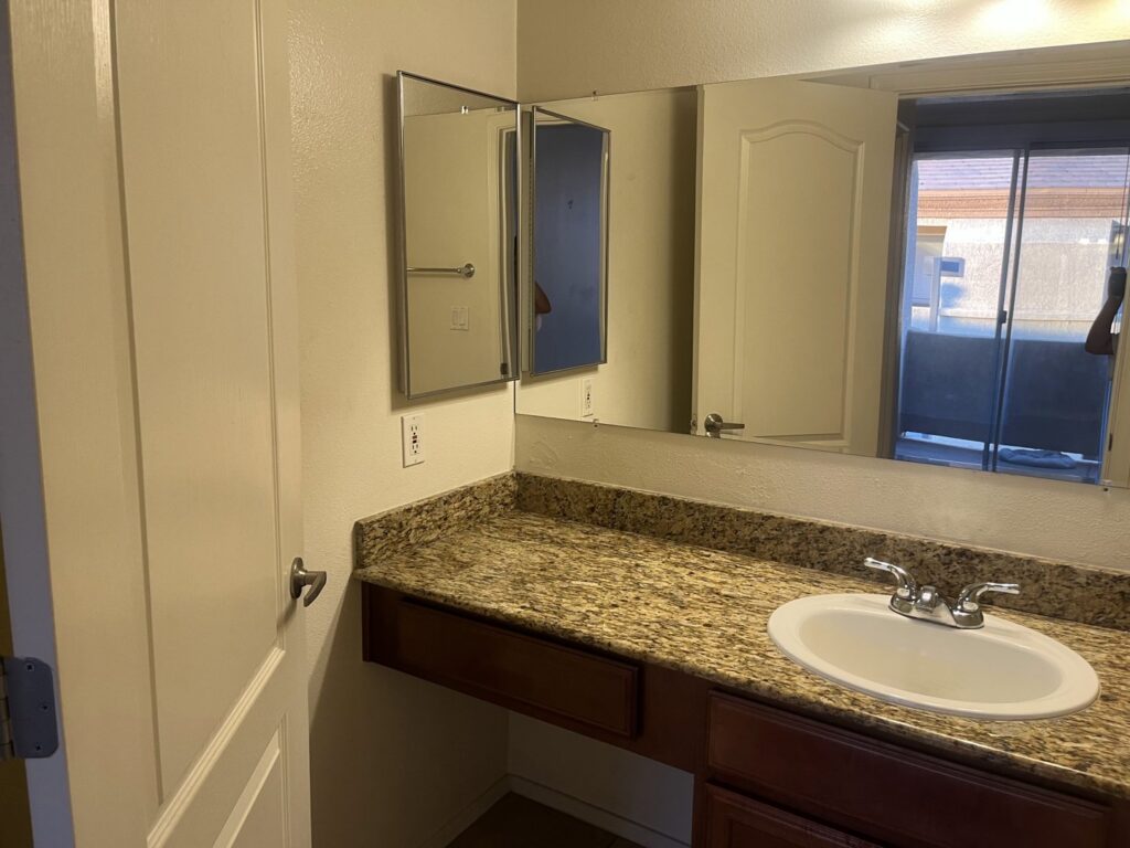 A spotless bathroom vanity with a white sink and granite countertop, reflecting the thorough cleaning services of Carole's House Cleaning in Tempe, AZ.