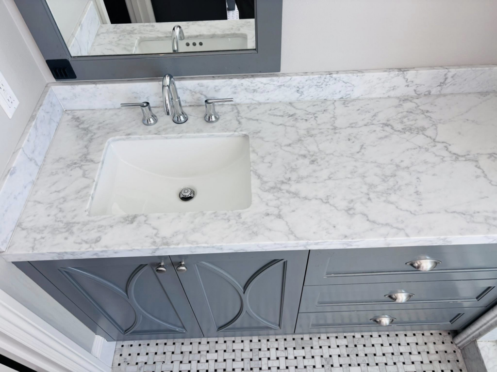 A clean bathroom vanity with a white sink and polished marble countertop by Clean departure Cleaning service in Reseda, CA.