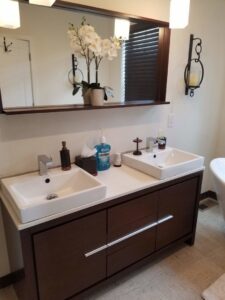 A clean bathroom vanity with two white sinks and a large mirror by Cooper-N-Folks in Philadelphia, PA