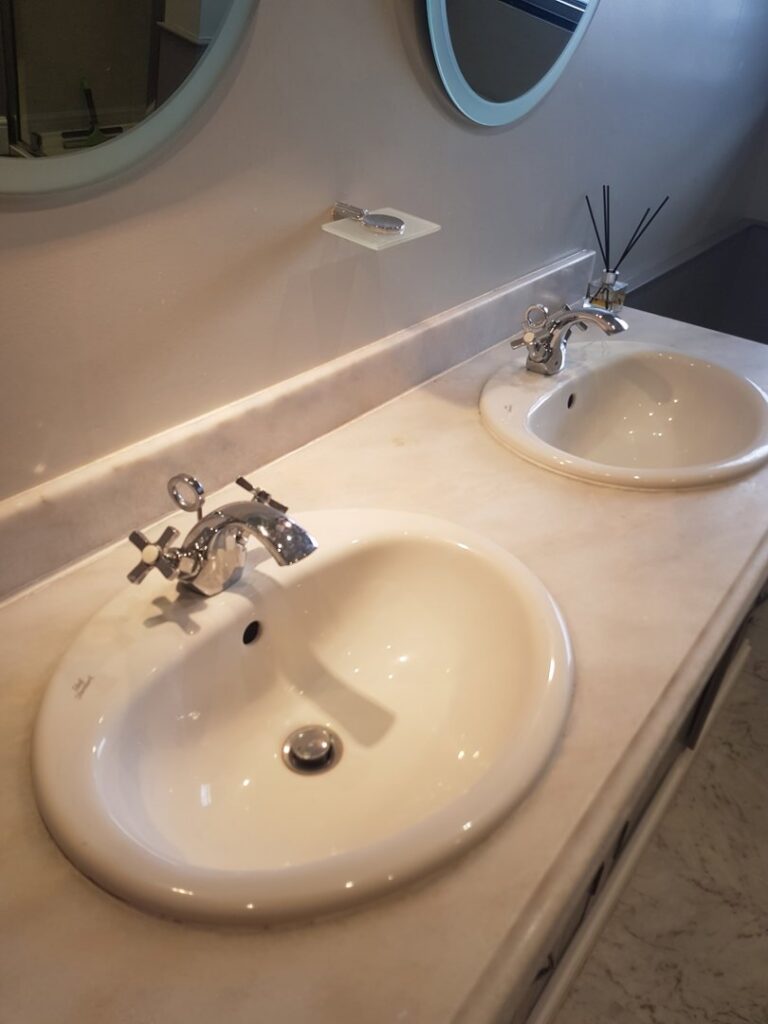 A clean bathroom vanity with two white sinks and polished faucets, demonstrating a professionally cleaned space by Pretty & Polished Cleaning Services in Sandy, OR.