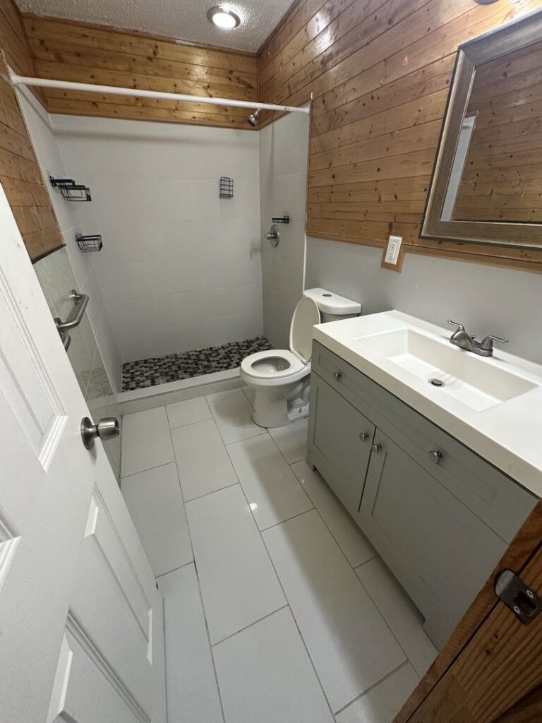 A clean bathroom featuring a vanity, toilet, and shower, showcasing the professional cleaning by CLEAN That SHEET LLC in Jacksonville, FL.