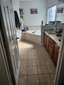A clean bathroom with a tiled floor, wooden vanity, and corner bathtub, professionally cleaned by S&M Cleaning Services 5 LLC in Cocoa, FL.