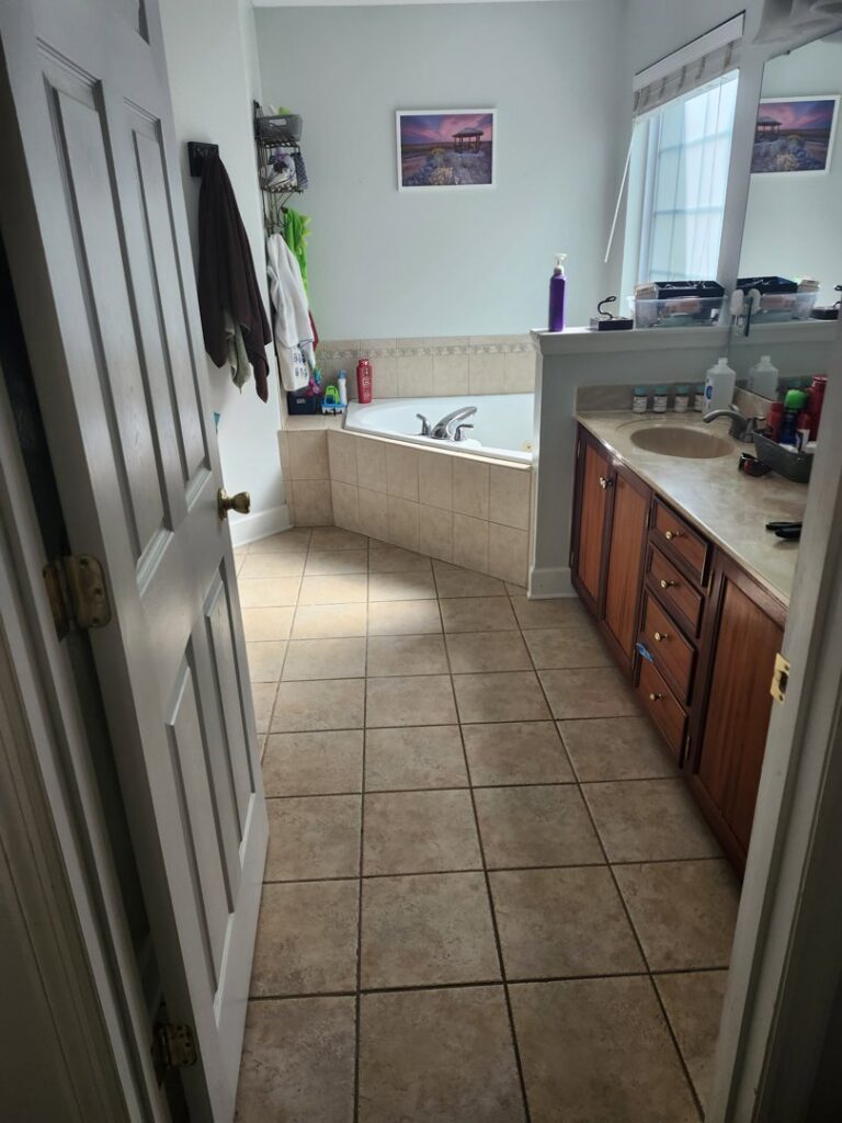A clean bathroom with a tiled floor, wooden vanity, and corner bathtub, professionally cleaned by S&M Cleaning Services 5 LLC in Cocoa, FL.