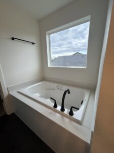 A pristine white bathtub with modern black fixtures, professionally cleaned by Martinez Cleaning Services in Kent, WA
