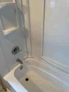 A clean white bathtub and shower enclosure after professional house cleaning by Teri Lynn's Cleaning in Williston, ND.