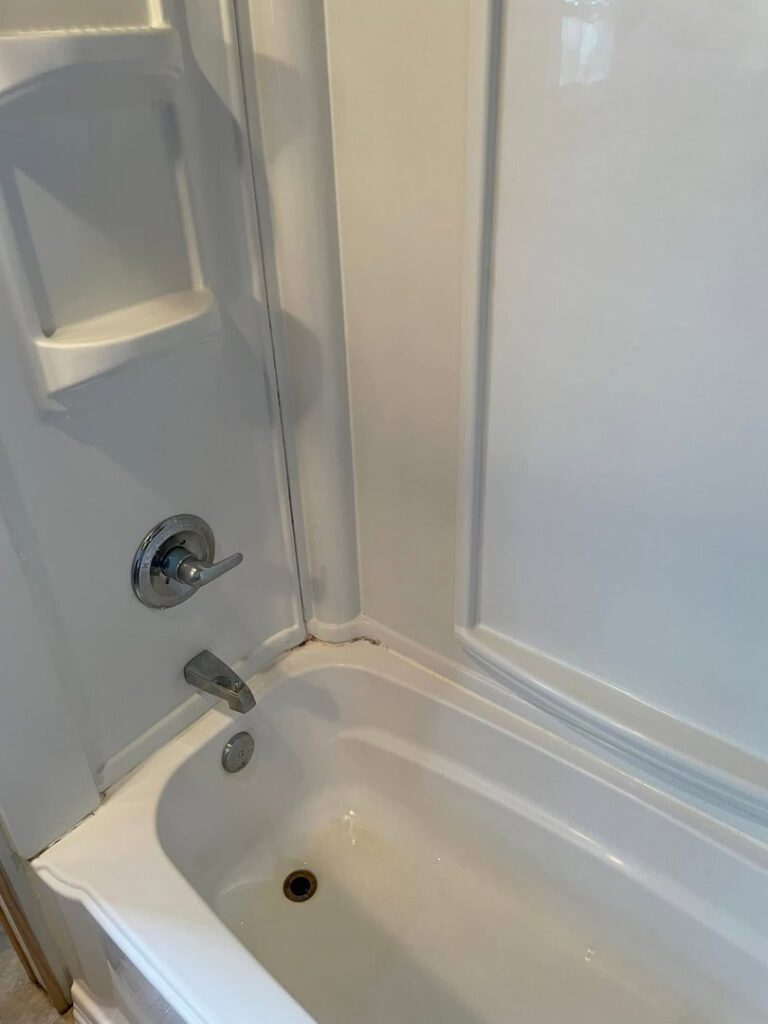 A clean white bathtub and shower enclosure after professional house cleaning by Teri Lynn's Cleaning in Williston, ND.