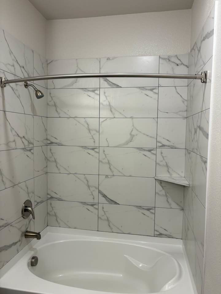 A pristine bathtub and shower with clean tiles, professionally cleaned by Jess Cleaning in San Antonio, TX.