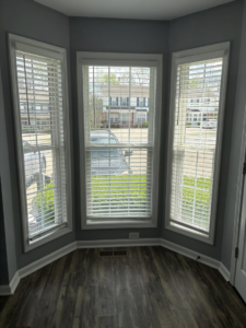 A sparkling clean bay window area with blinds and a polished wooden floor, showcasing the results of Claudia's Cleaning Services in Clarksville, TN.