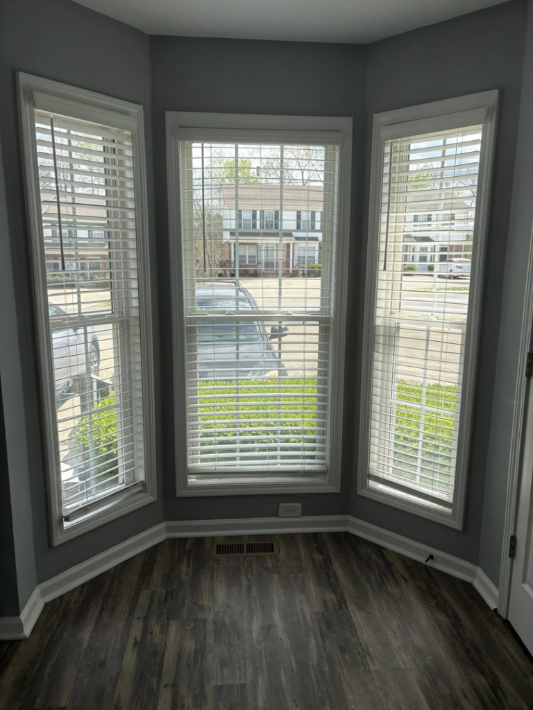 A sparkling clean bay window area with blinds and a polished wooden floor, showcasing the results of Claudia's Cleaning Services in Clarksville, TN.
