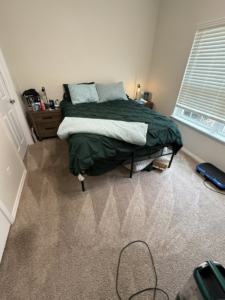 A clean bedroom with a neatly made bed and vacuumed carpet, after house cleaning by WWJM Cleaning Service in Oklahoma City, OK.