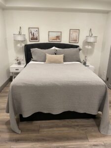 A neatly made bed in a clean bedroom with bedside tables and lamps, demonstrating the thorough house cleaning by Cleans by Roseileen LLC in Louisville, KY.