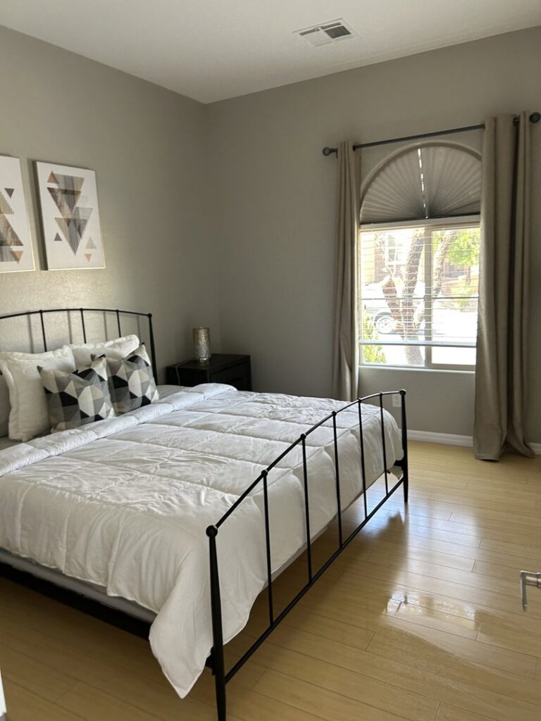 A clean bedroom featuring a neatly made bed and polished hardwood floors, maintained by JG Clean Solutions in Henderson, NV.