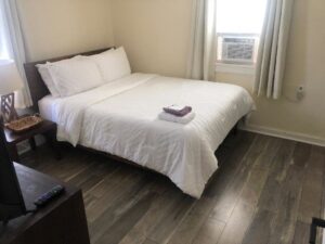 A neatly made bed in a clean bedroom, showcasing results from The Blake Experience Cleaning Service in Albany, NY.