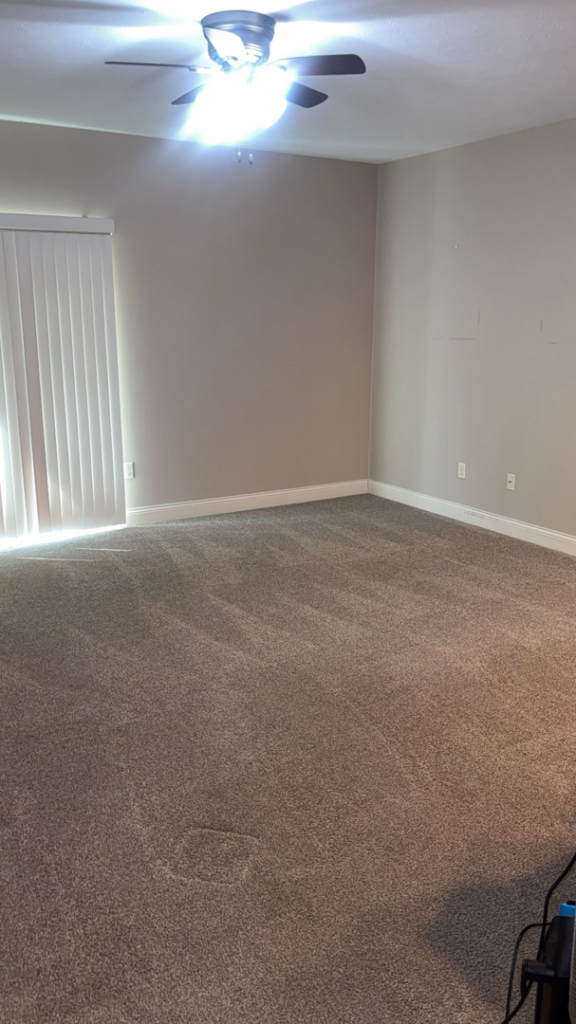 A spacious, clean carpeted room with a ceiling fan and sliding door, reflecting professional house cleaning by NACleaning Co. in Omaha, NE.