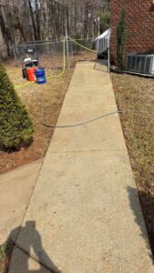 A clean concrete sidewalk after professional power washing by Plains Power Washing in Auburn, AL, with equipment visible.